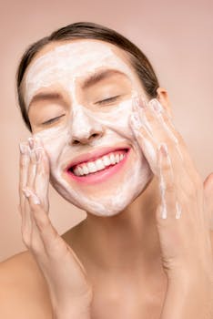 Smiling woman applies facial wash while enjoying her skincare routine, promoting happiness and skin health.